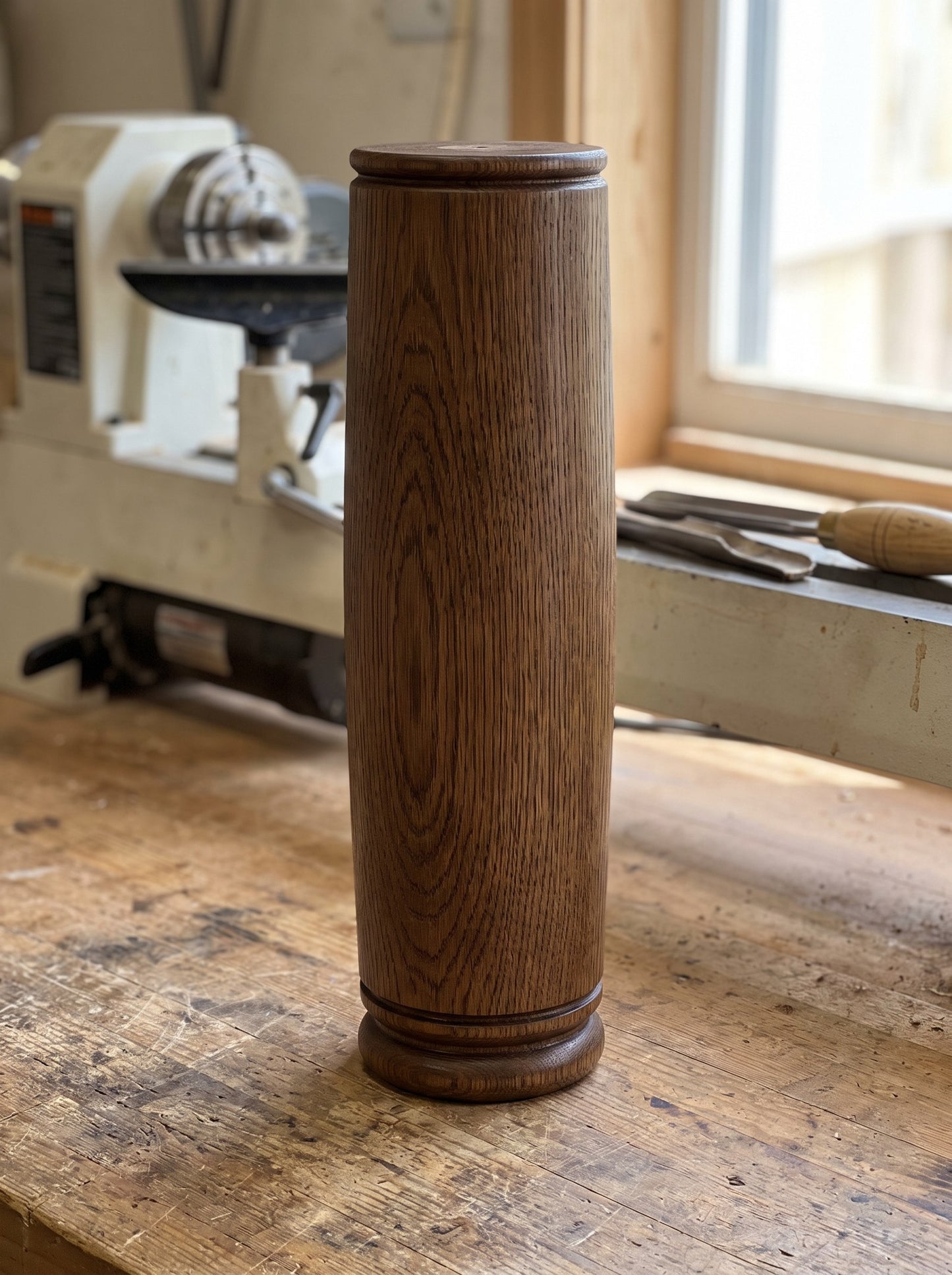 A heavy fumed oak Floodgate column leg standing on the workshop floor beside the lathe it was turned on