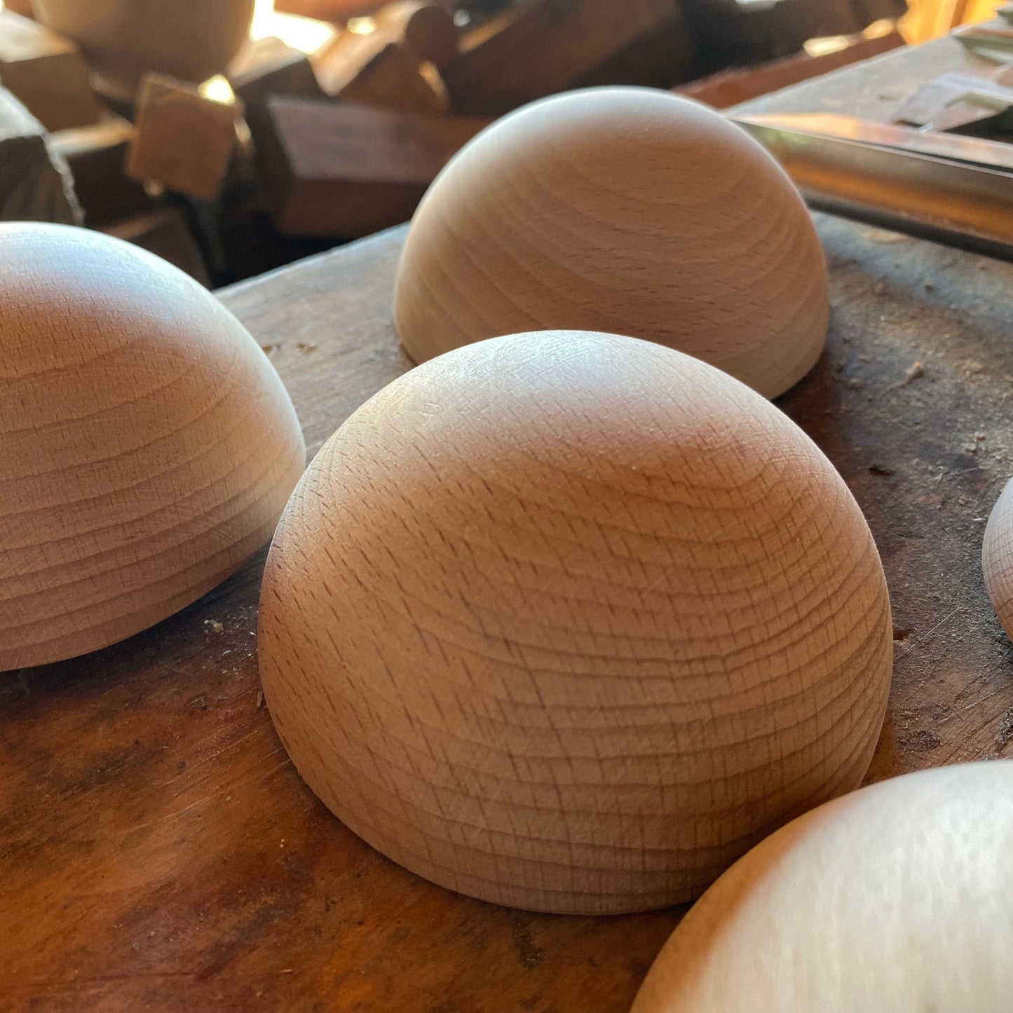 Hand-crafted wooden hemispheres on a crafting table, made from natural redwood.